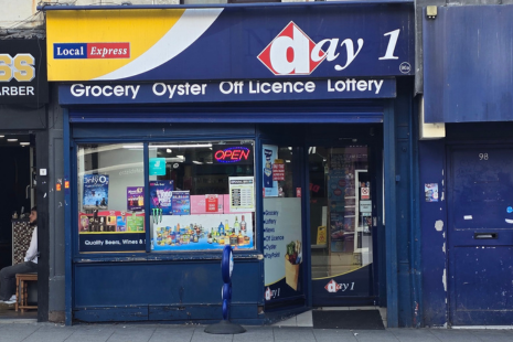 Image showing the exterior of 'day 1 Local Express' with blue, yellow and white branding.  The shop is blue, and white text under the sign reads 'Grocery  Oyster  Off Licence  Lottery'