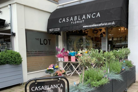 Image showing the exterior of Casablanca Florist in Shenfield, with black awning and white text. Plants and bunches of flowers are visible outside.