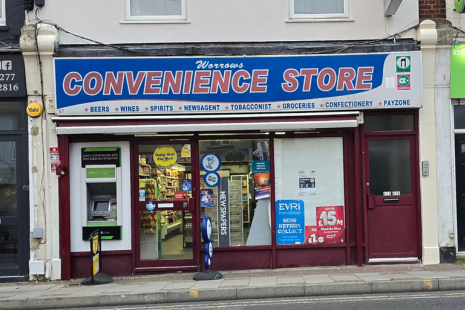 Inage showing the exterior of Worrows Convenience Store with red text on a blue background.  There is a lottery sign outside and stickers in the windows.