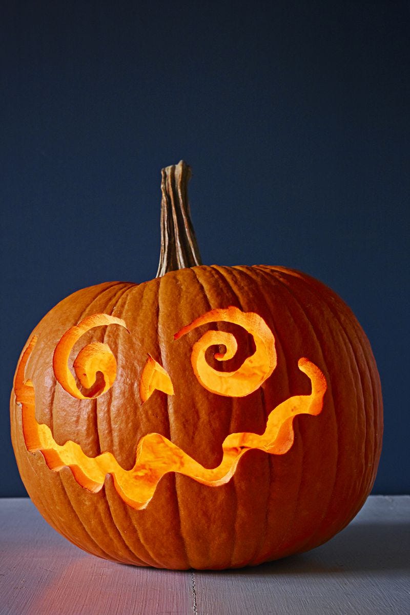 Image of a carved pumpkin with eyes, a mouth and a nose, lit inside.