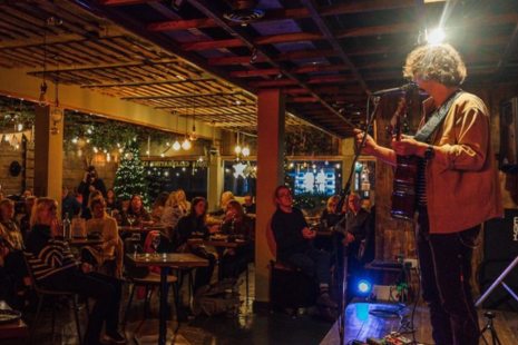 Image of a performer with a guitar on stage, watched by a crowd of people, at The Country Cafe in Ingatestone