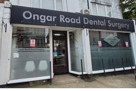 Image of the exterior of Ongar Road Dental Surgery with glass frontage and silver and black signage.