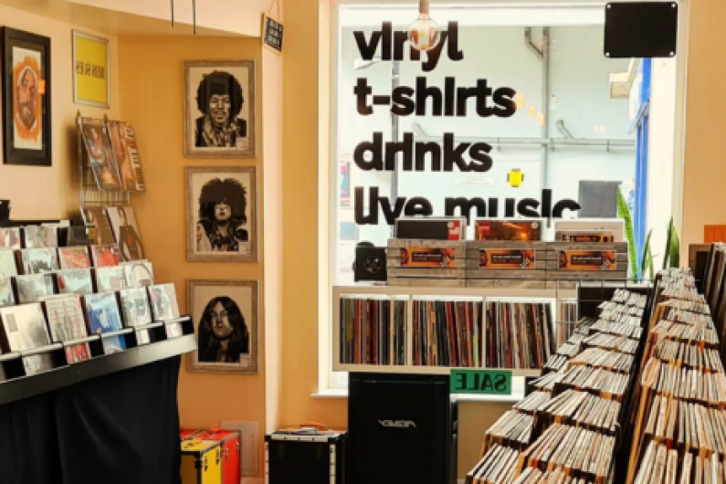 Image showing the interior of Hey Joe Music & Coffee - records are visible, along with artwork of musicians, and signage on the window which says 'vinyl, t-shirts, drinks, live music'.