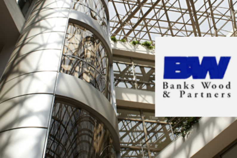 Modern office building interior with a glass atrium and metal framework, featuring the logo of 'Banks Wood & Partners' in the top right corner. The logo includes the initials 'BW' in bold blue letters, with the full company name written below.