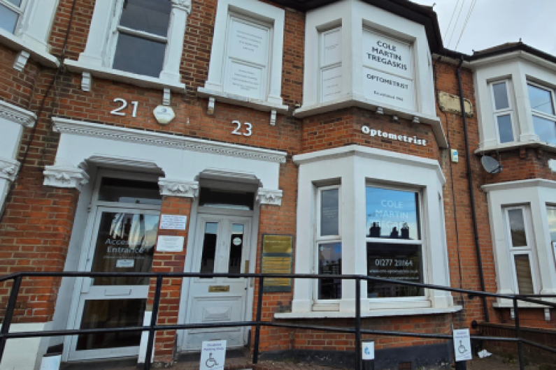 Exterior of a brick building housing Cole Martin Tregaskis Optometrists, located at 23 Shenfield Road.  Number 21 is also visible. The building features large windows displaying the optometrist's name and contact details. There is an accessible entrance with a ramp and signs indicating wheelchair access.