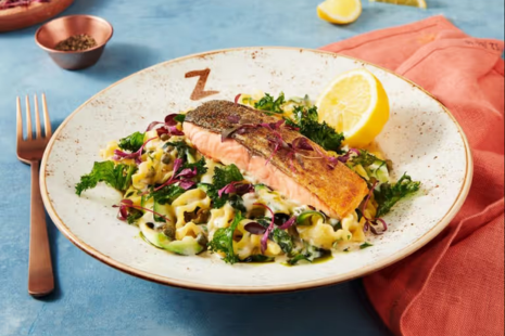 A bowl of salmon on pasta with a lemon.  A 'Z' is printed on the bowl.