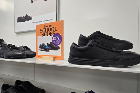 Image of a pair of black school shoes at Clarks, with a sign including details about its 'Buy any SCHOOL SHOES get £10 off selected sports shoes' offer