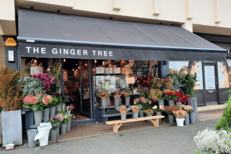 Exterior of The Ginger Tree with colourful bouquets outside and a black awning.