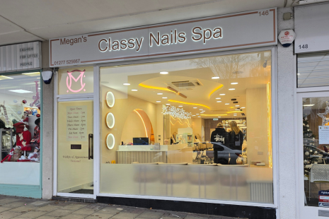 Exterior of Megan's Classy Nails Spa with a bright yellow glow from inside.